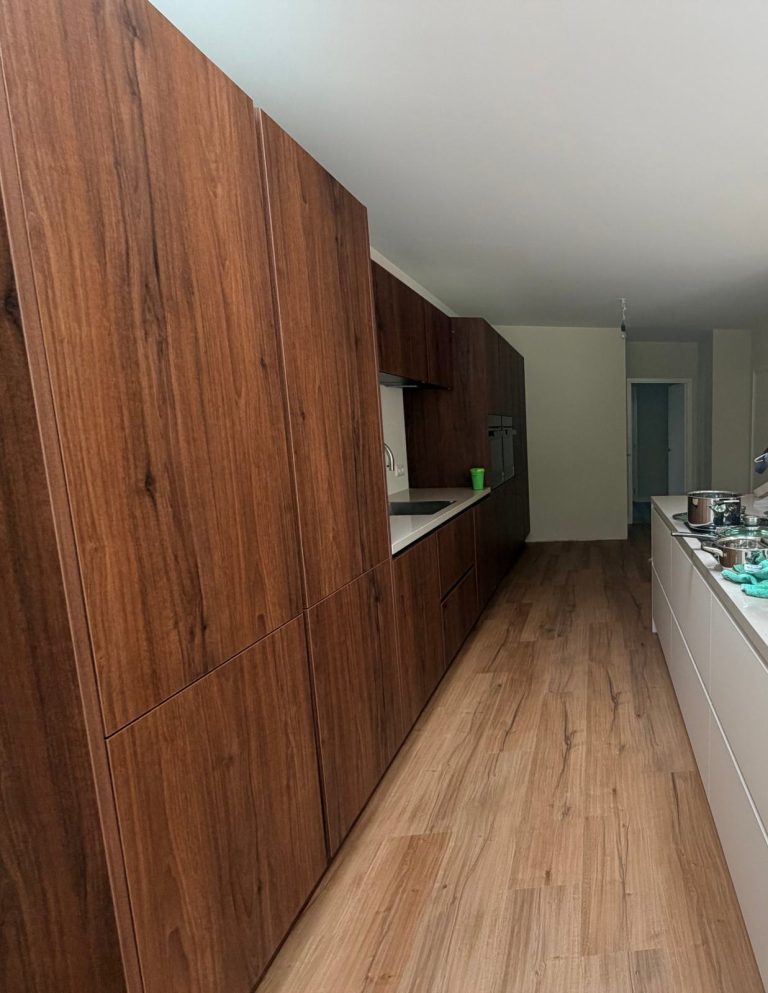 Keuken met kastenwand in warme houtlook en kookeiland na de totaalrenovatie