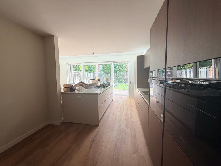Nieuwe keuken met kookeiland en hoge kasten in houtlook